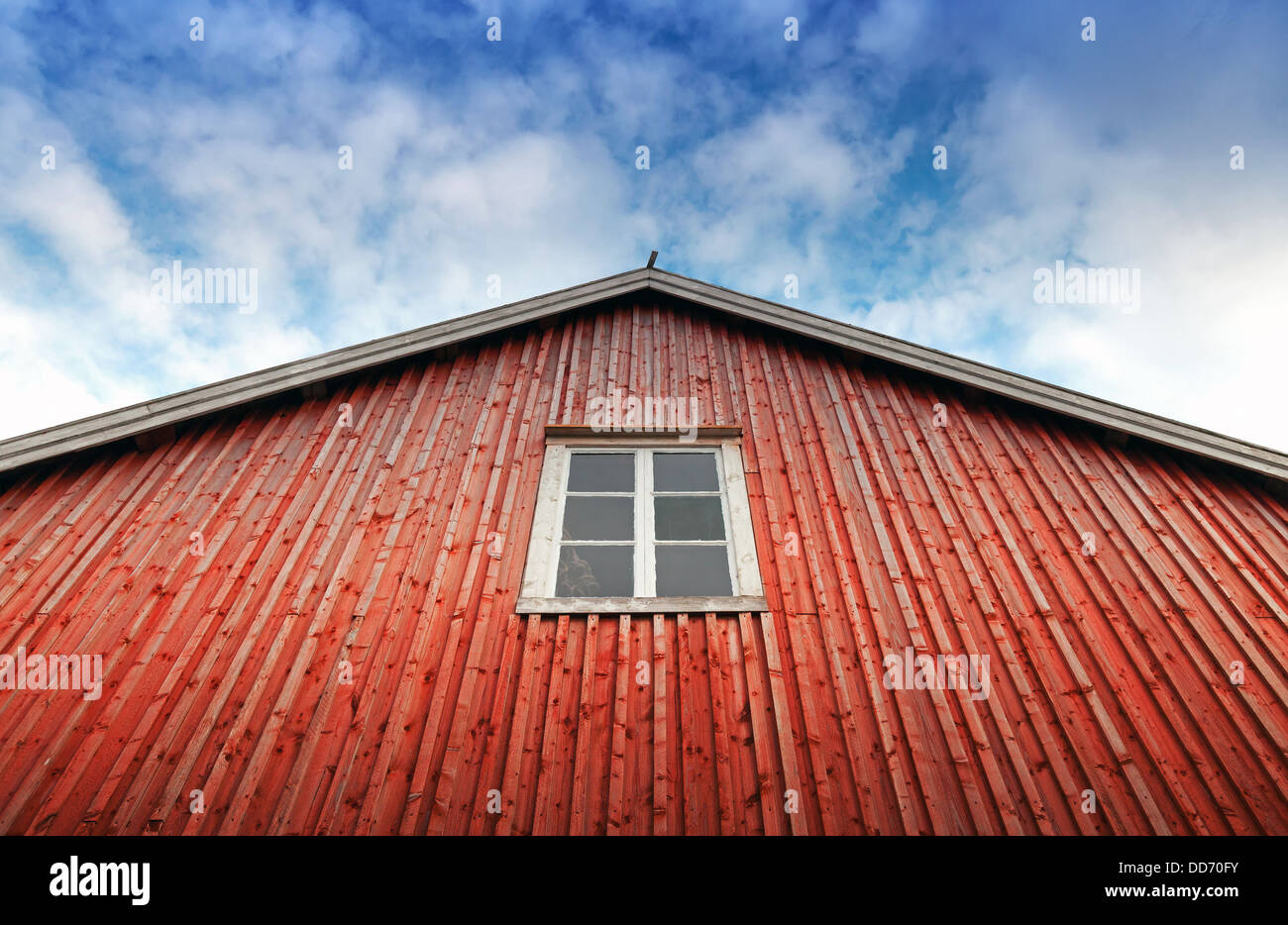 Rosso parete in legno con sopra la finestra blu cielo nuvoloso. Tipicamente casa di pesca in Norvegia Foto Stock