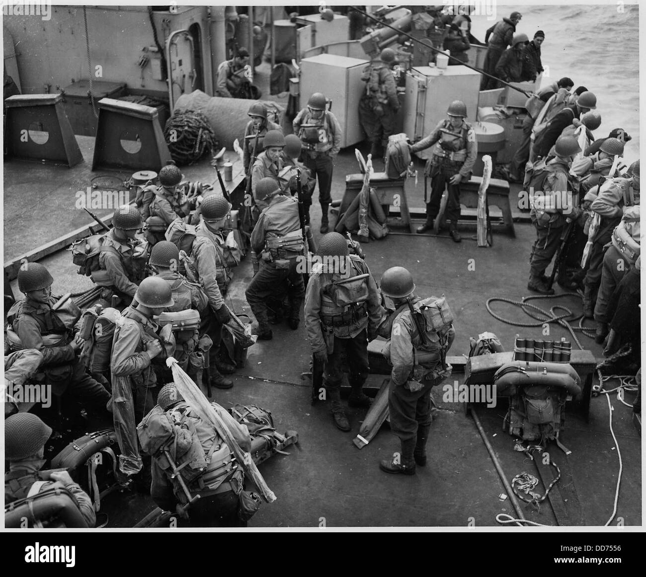 I soldati americani, dotati di equipaggiamento da combattimento completo, si rilassano sul ponte di una nave d'assalto della Guardia Costiera. L'immagine cattura i soldati in un momento di riposo prima di intraprendere operazioni militari. Foto Stock