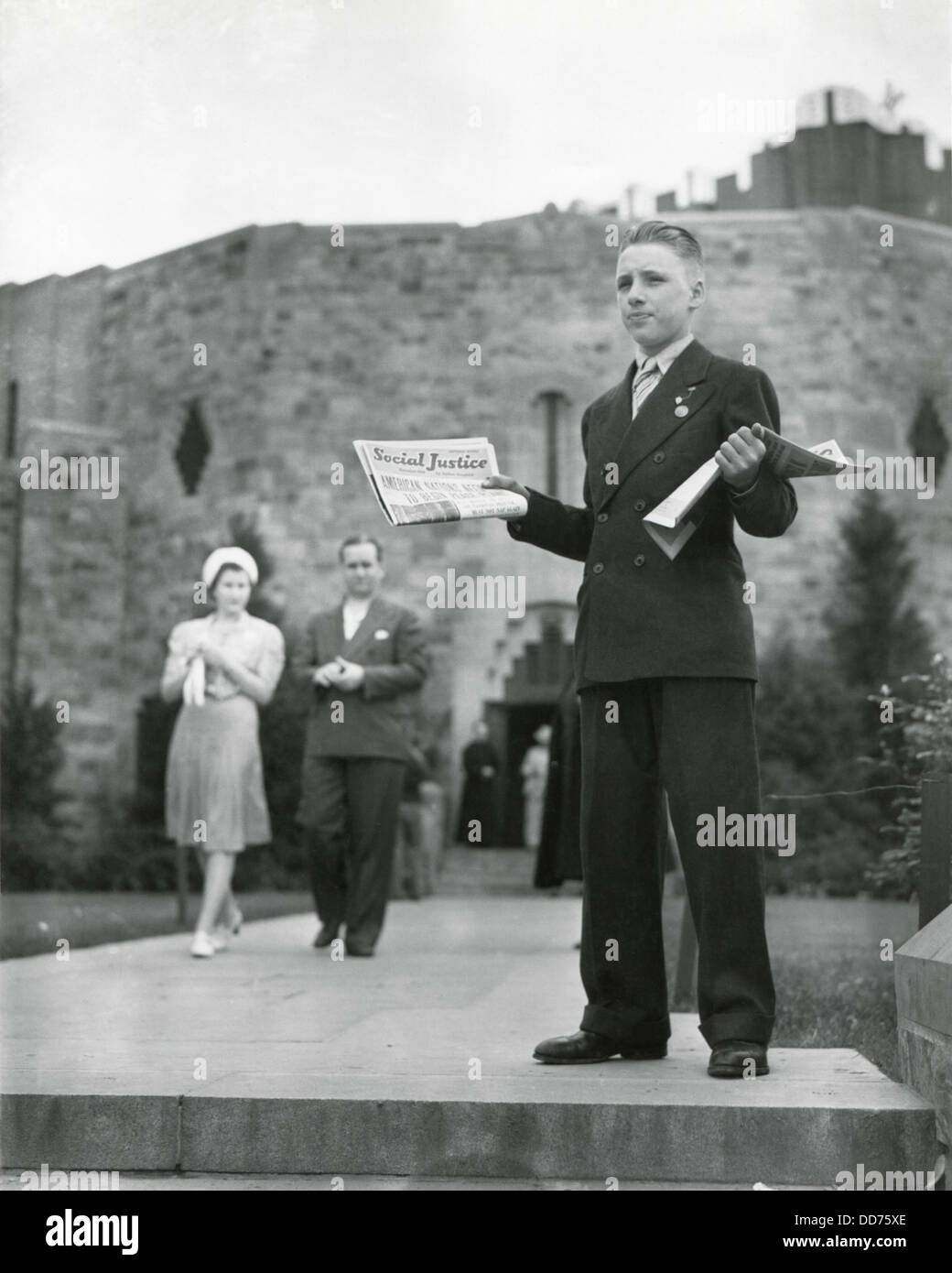Adolescente vendita di padre Coughlin del quotidiano, 'sociale giustizia", luglio 1940. Dietro di lui è la 'Shrine del Piccolo Fiore' Foto Stock