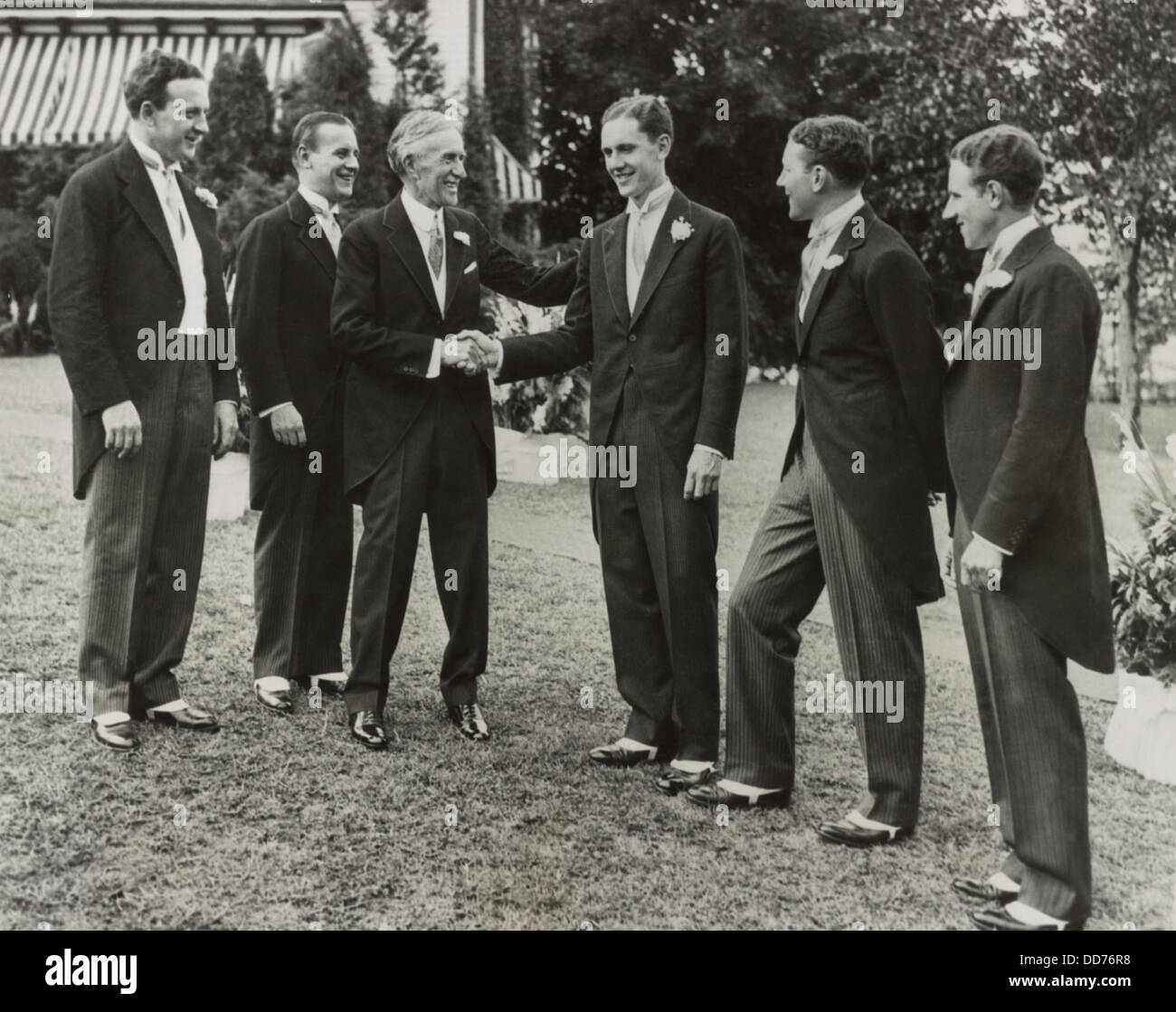 Harvey Firestone congratulandosi con il suo figlio più giovane Roger al suo matrimonio, Agosto 22, 1930. Rogers quattro fratelli più anziani a guardare. Foto Stock