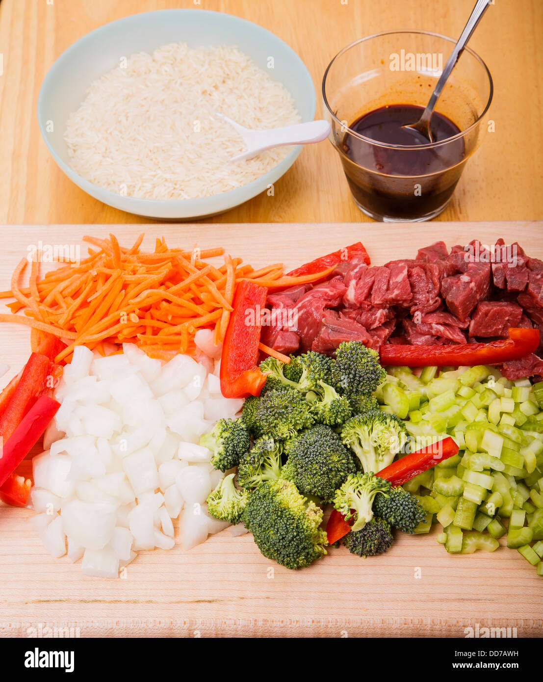 Carni bovine friggere ingredienti sul tagliere con il riso e la salsa di soia in background Foto Stock