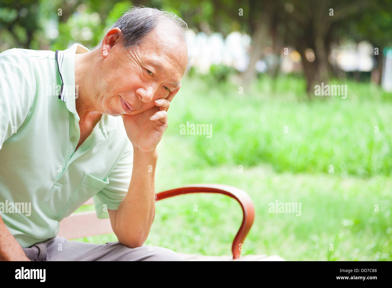 Premuto senior uomo seduto nel parco Foto Stock