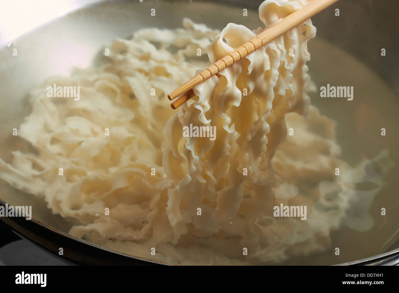 Ebollizione di noodle cinesi in un wok in acciaio Foto Stock