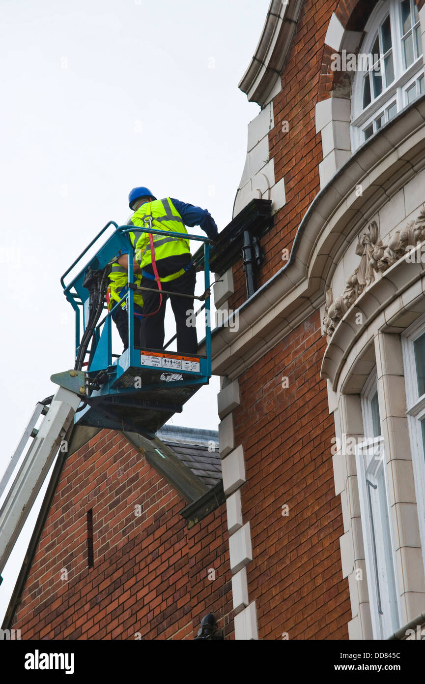 Imprenditori in alto la piattaforma di accesso rendere sicuro un edificio dopo essere stata danneggiata da un fulmine nella città di York England Regno Unito Foto Stock