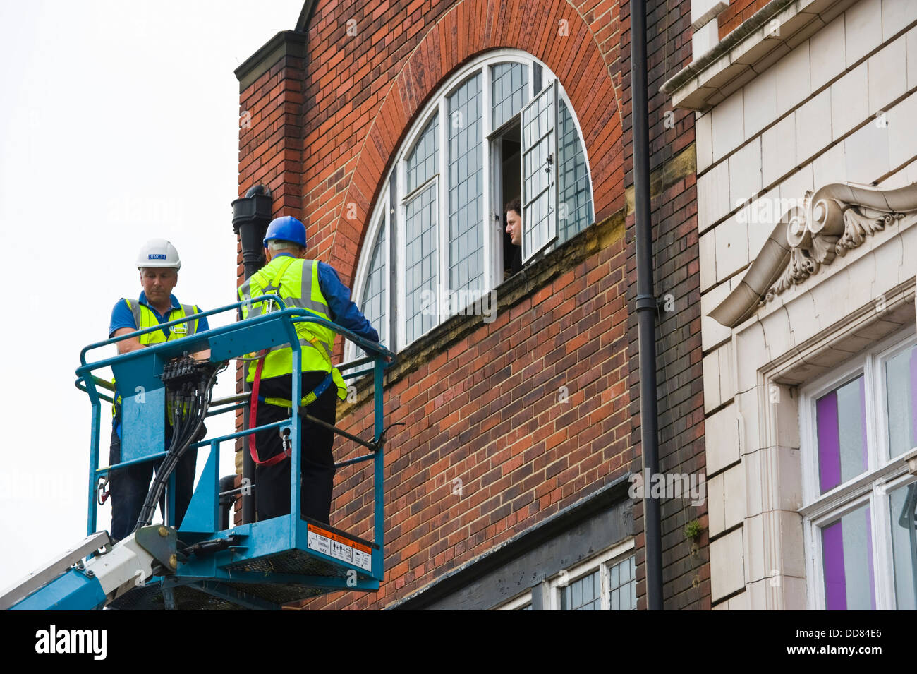Imprenditori in alto la piattaforma di accesso rendere sicuro un edificio dopo essere stata danneggiata da un fulmine nella città di York England Regno Unito Foto Stock