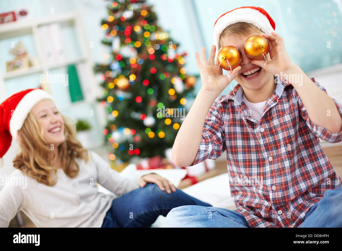 Ritratto di felice lad azienda giocattolo decorativi sfere dai suoi occhi e ridere della sera di Natale Foto Stock