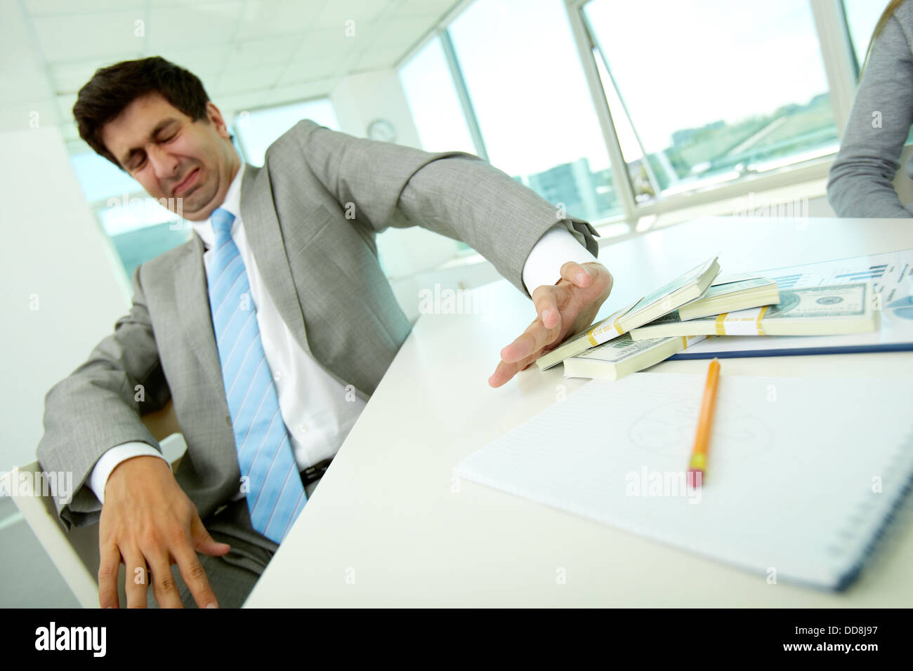Immagine di disgustato dipendente di sesso maschile spostando le fatture del dollaro lontano e rifiutando di prendere tangenti Foto Stock