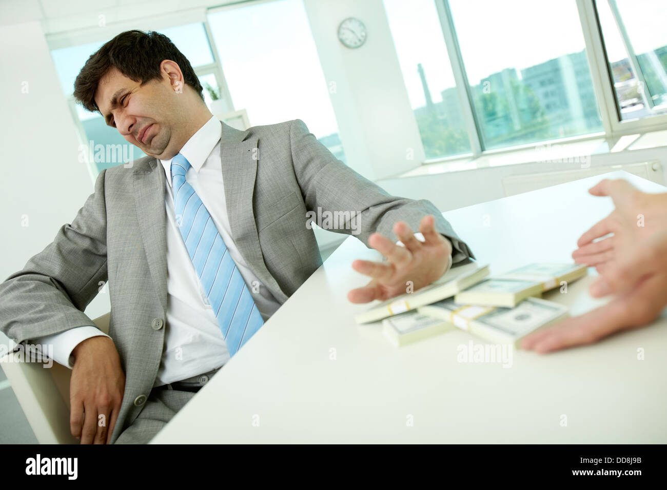 Immagine di disgustato dipendente di sesso maschile spostando le fatture del dollaro lontano e rifiutando di prendere tangenti Foto Stock