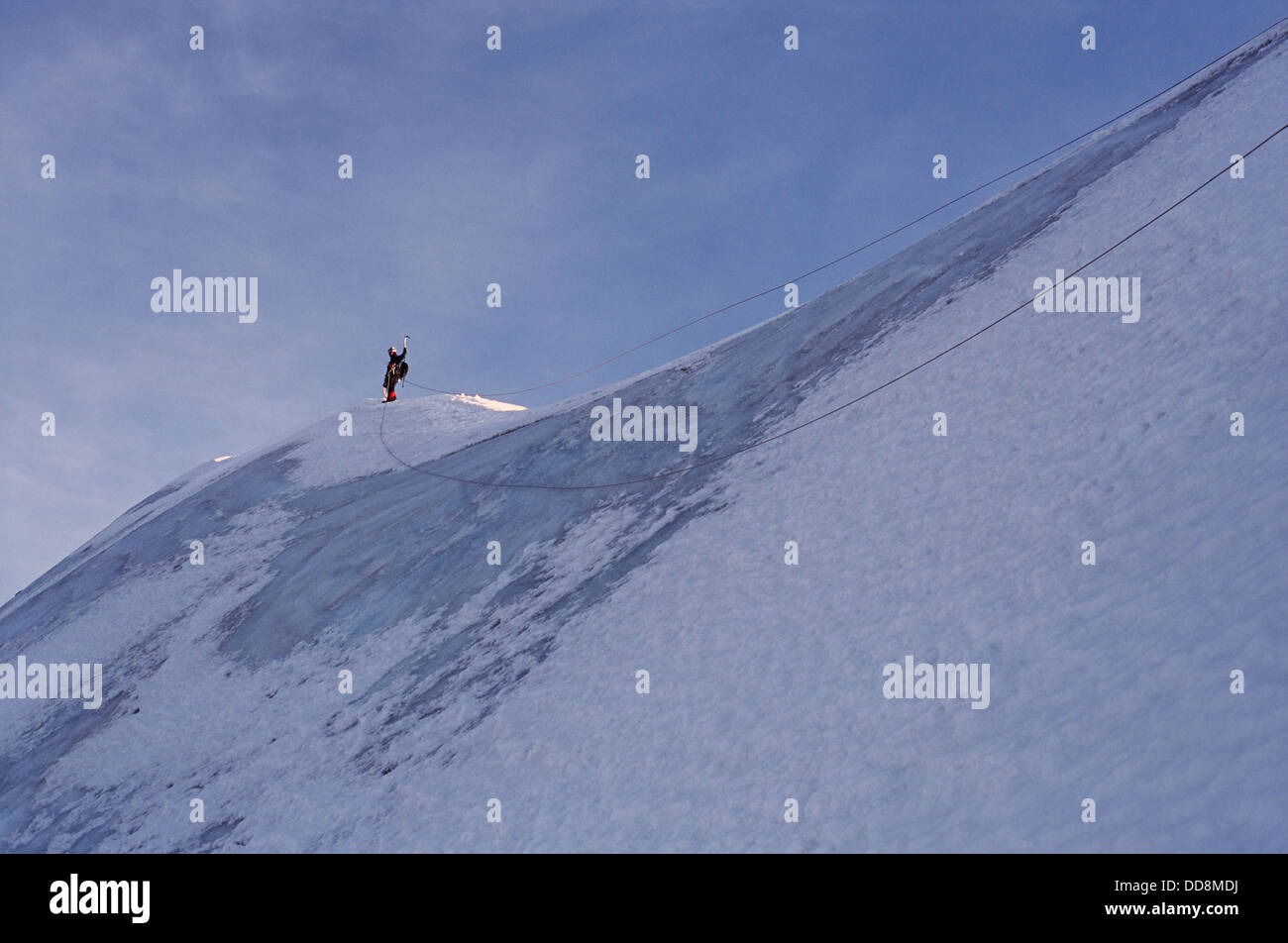 Vista bassa di alpinista legato con corda doppia che soggiornano sul vertice di les courtes. sulle alpi francesi, mont blanc gamma. l uomo raggiungendo il culmine godendo il successo. Foto Stock