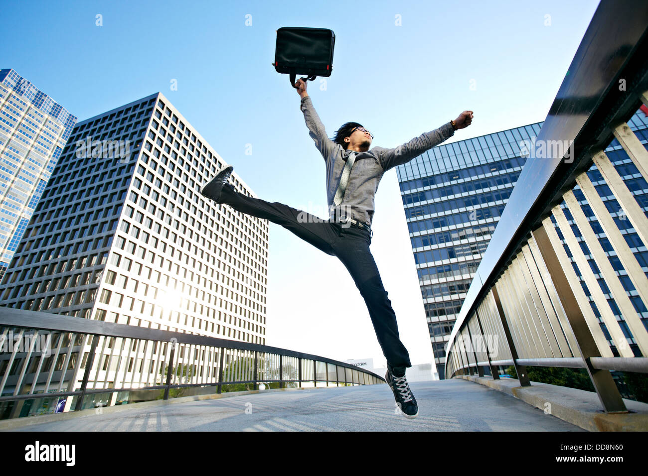 Imprenditore asiatico che saltava sulla passerella urbana Foto Stock