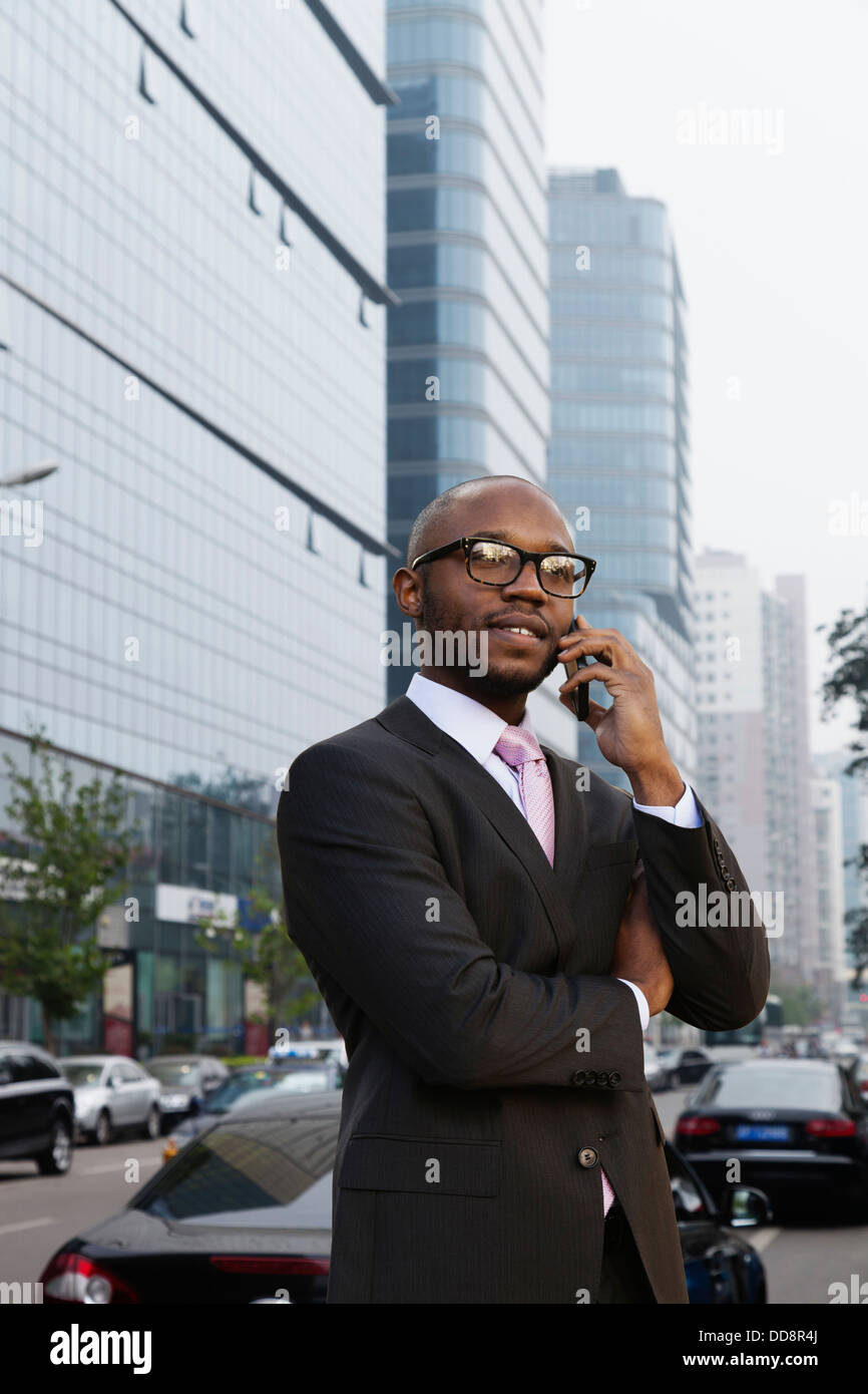 Imprenditore nero parlando al cellulare su una strada di città Foto Stock