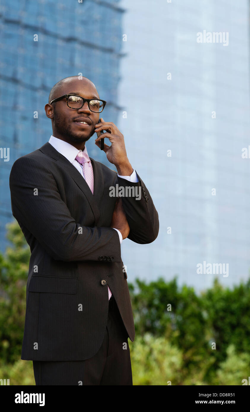 Imprenditore nero parlando al cellulare su una strada di città Foto Stock