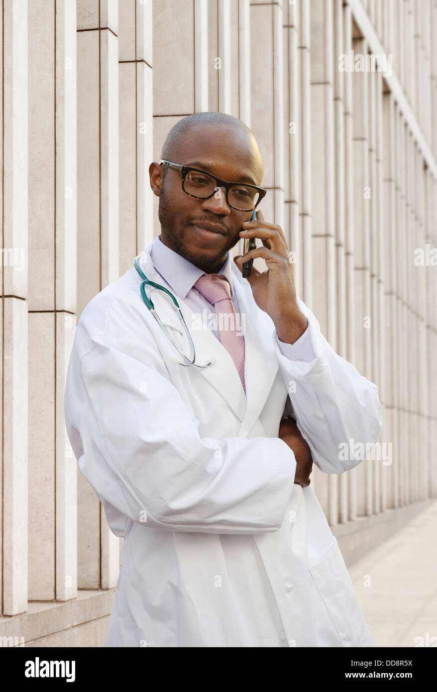 Medico nero parlando al cellulare su una strada di città Foto Stock