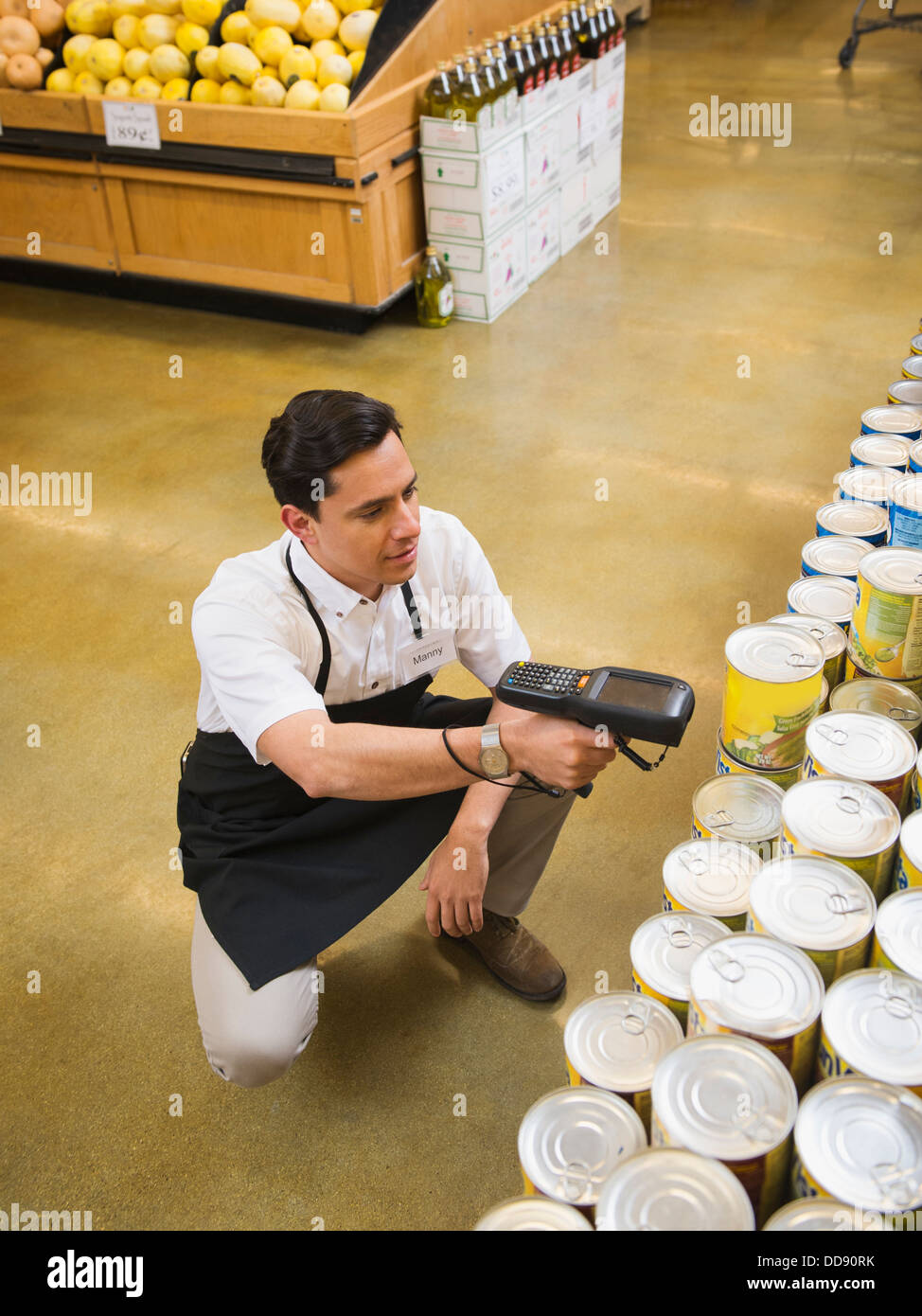 Lavoratore ispanica scansione degli articoli nel negozio di alimentari Foto Stock