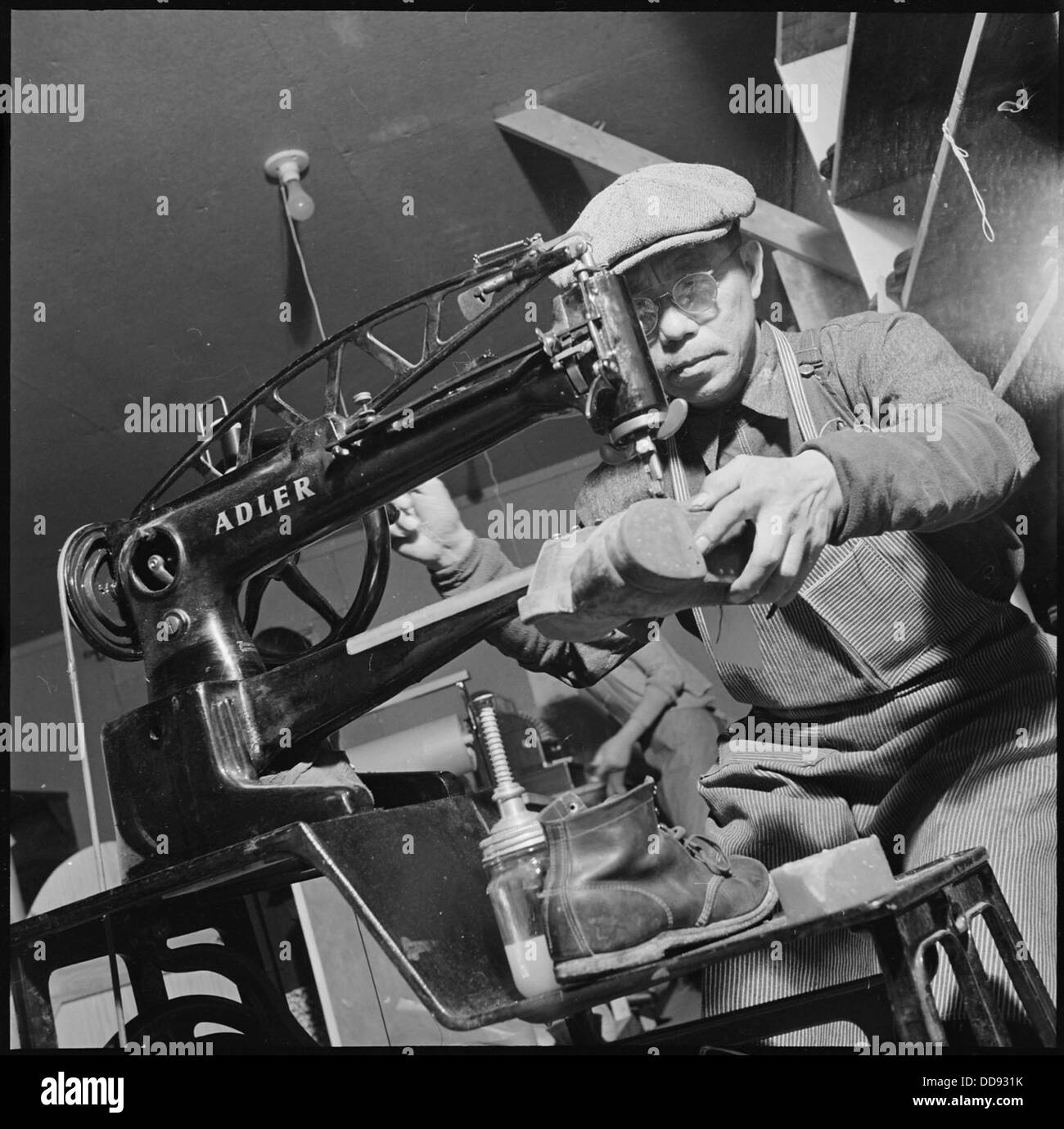 Un calzolaio al Heart Mountain Relocation Center in Wyoming gestisce una macchina come parte del programma di lavoro del campo durante la seconda guerra mondiale Foto Stock