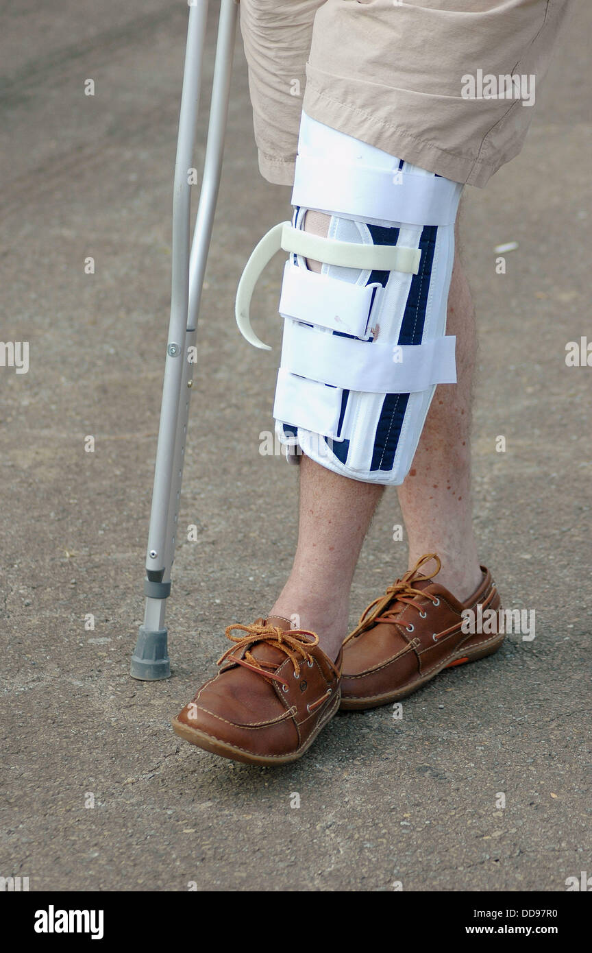Uomo in stampelle con rotto il ginocchio infortunato a piedi Foto stock -  Alamy