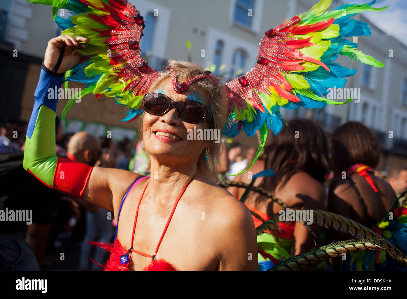 Una Donna vestita di piume colorate e e occhiali da sole il sorriso e la danza del sole. È l'ultima serata della sfilata. Foto Stock