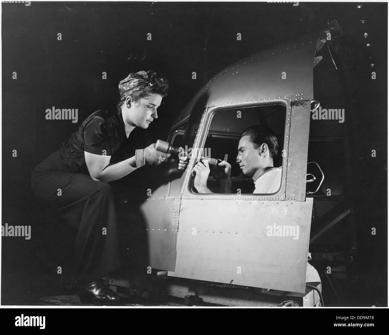 Un uomo e una donna gestiscono in modo efficiente macchinari per rivettatura presso lo stabilimento della Douglas Aircraft Company di Long Beach, California. Questo stabilimento ha giocato un ruolo chiave nella produzione di aeromobili durante la seconda guerra mondiale Foto Stock