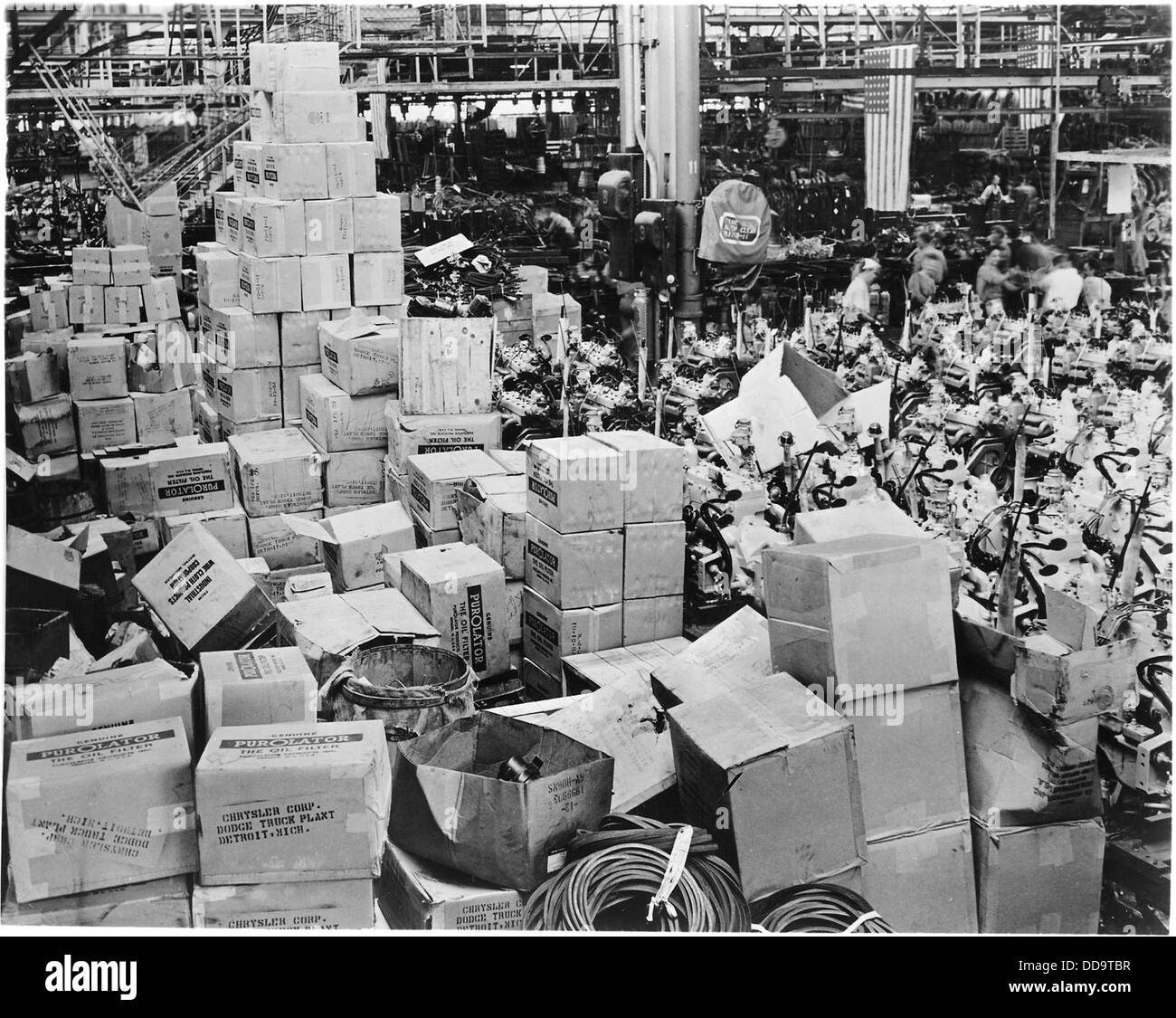 Questa immagine mostra un vasto inventario di accessori per camion dell'esercito, impilati quasi sul tetto e che occupano un'ampia area del pavimento. Mette in evidenza la portata dello stoccaggio di forniture militari, con attrezzature pronte per l'uso o la distribuzione per supportare le operazioni dell'esercito. Foto Stock