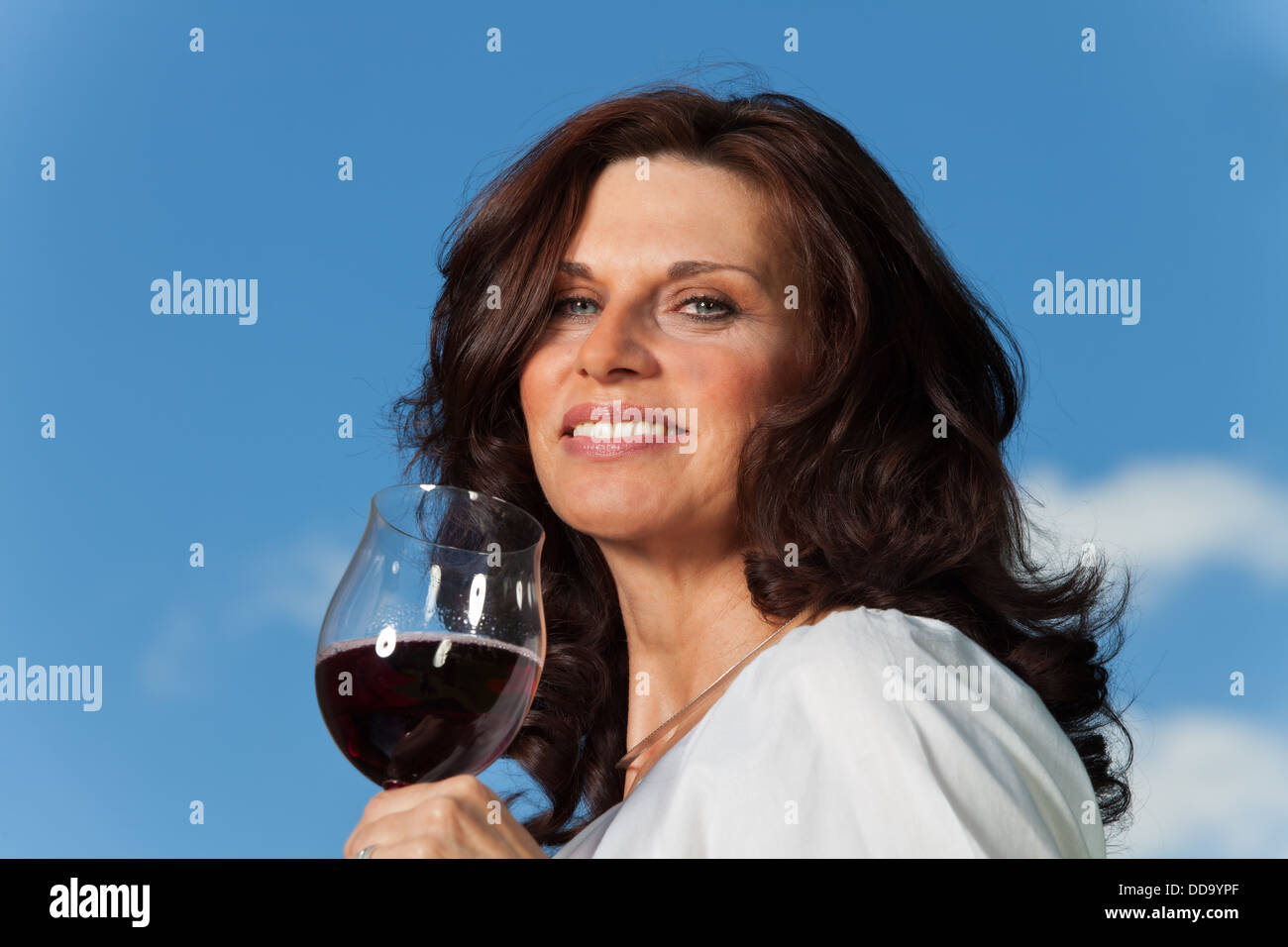 Donna felice con un bicchiere di vino rosso all'aperto Foto Stock