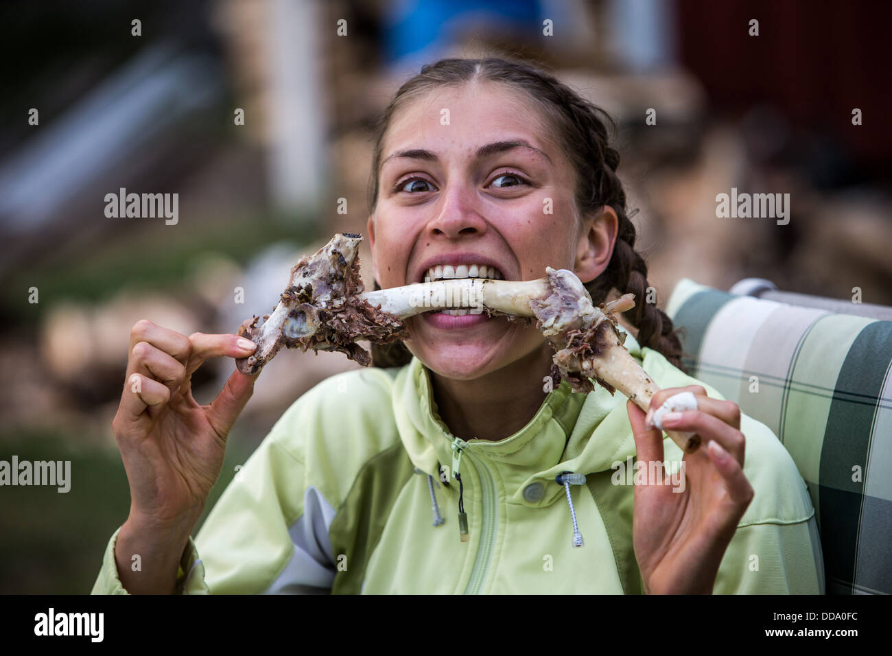 Donna di mangiare carne fuori un osso Foto Stock