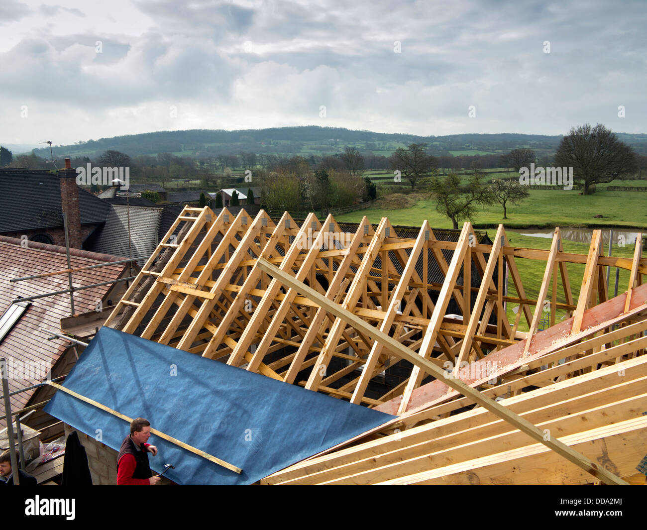 Auto casa Costruzione, costruzione tetto, iniziando a fissare il tetto traspirante membrana e listelli su capriate Foto Stock