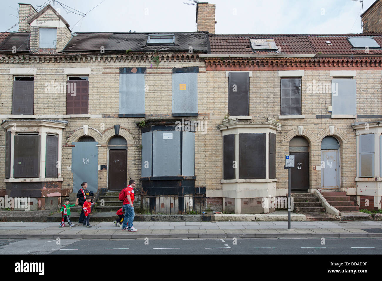 Una famiglia di sostenitori di Liverpool a piedi passato condannato le case di Anfield sulla strada per lo stadio (solo uso editoriale). Foto Stock