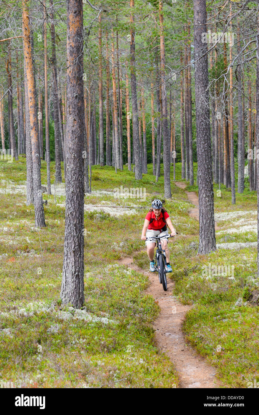 Donna in bicicletta sul percorso attraverso i boschi, Rörbäcksnäs, Dalarna, Svezia Foto Stock