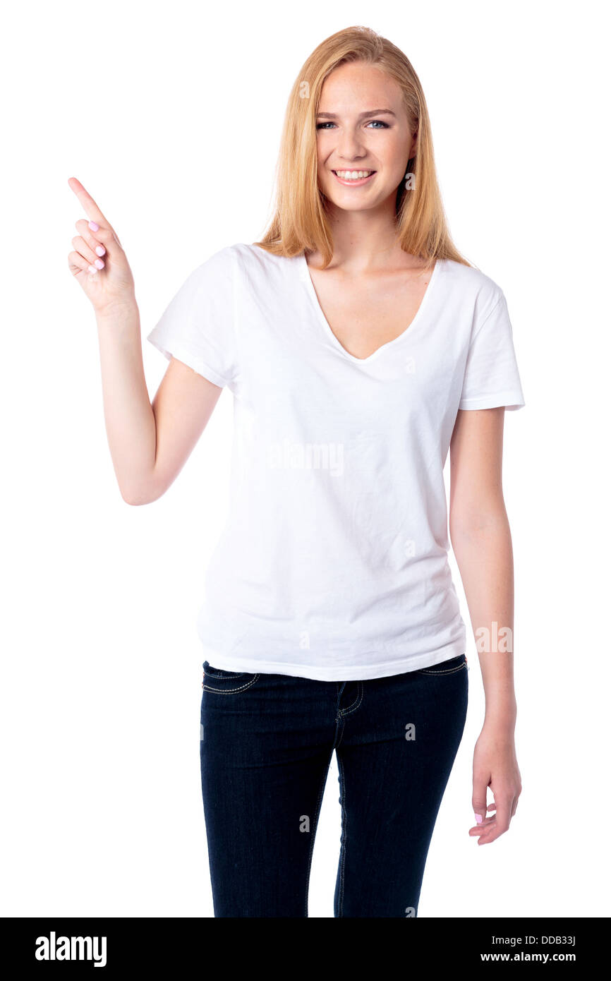 Sorridente attraente giovane donna in piedi rivolto verso l'alto con il suo dito verso copyspace vuoto , tre quarti su bianco Foto Stock