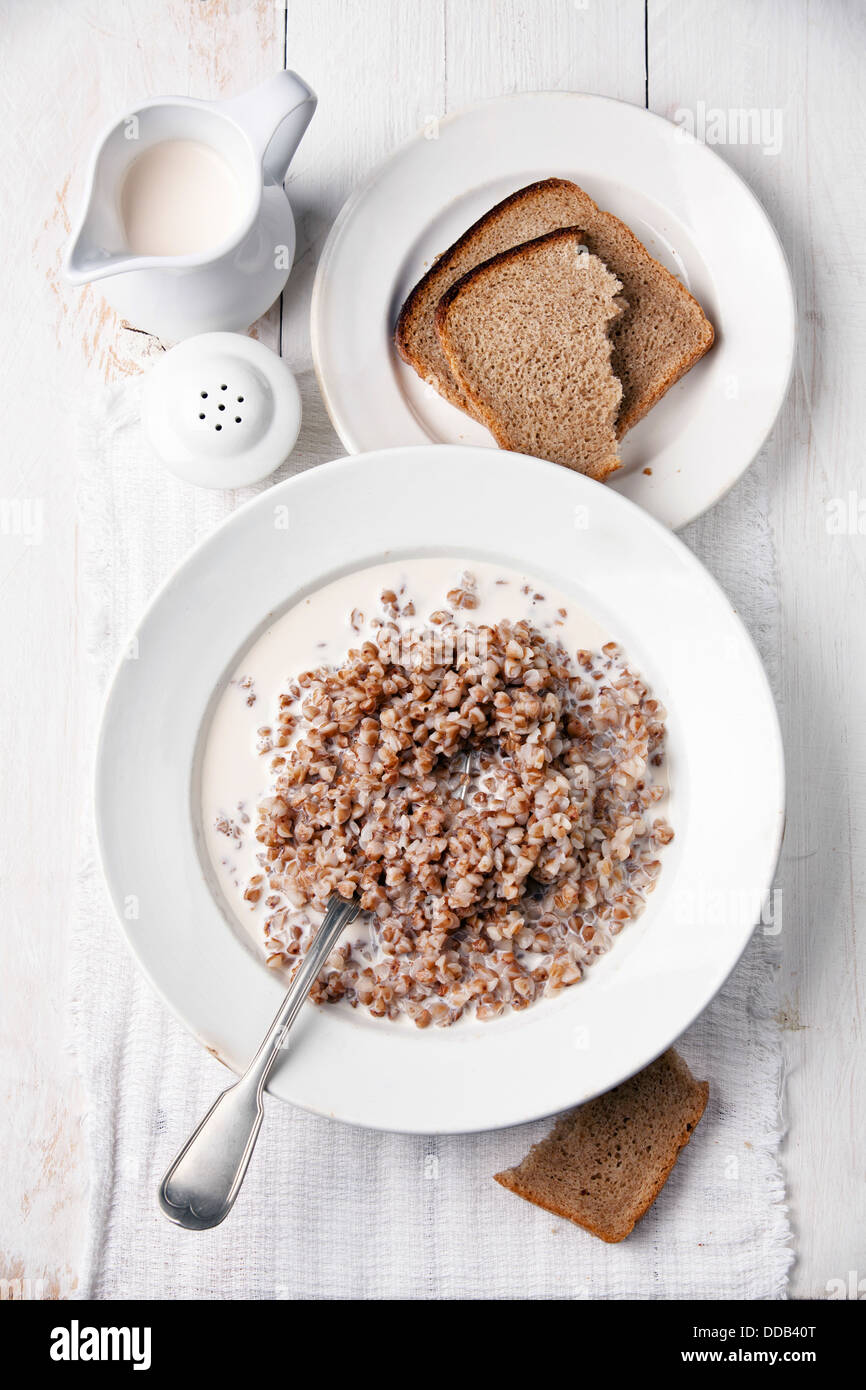 Bollito di grano saraceno con latte sulla tavola servita su bianco sullo sfondo di legno Foto Stock