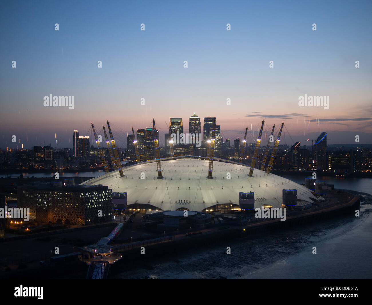 Moderno stadio coperto accanto ai grattacieli e corsi d'acqua in una città moderna, di notte Foto Stock