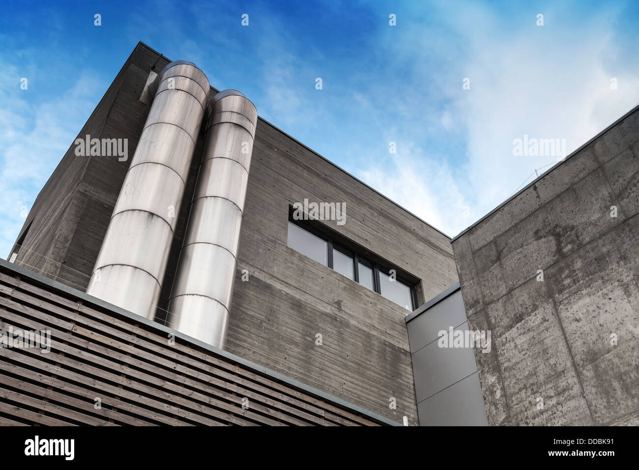 Frammento di astratta di cemento grigio edificio industriale con tubi metallici Foto Stock