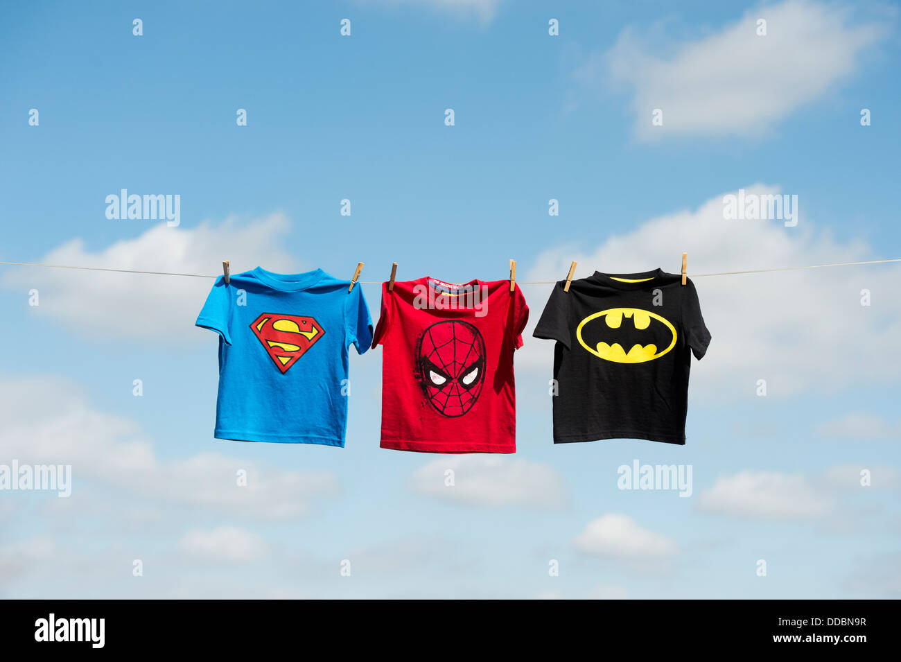 Childs Superman, Batman e spiderman t shirts appeso su una linea di lavaggio Foto Stock