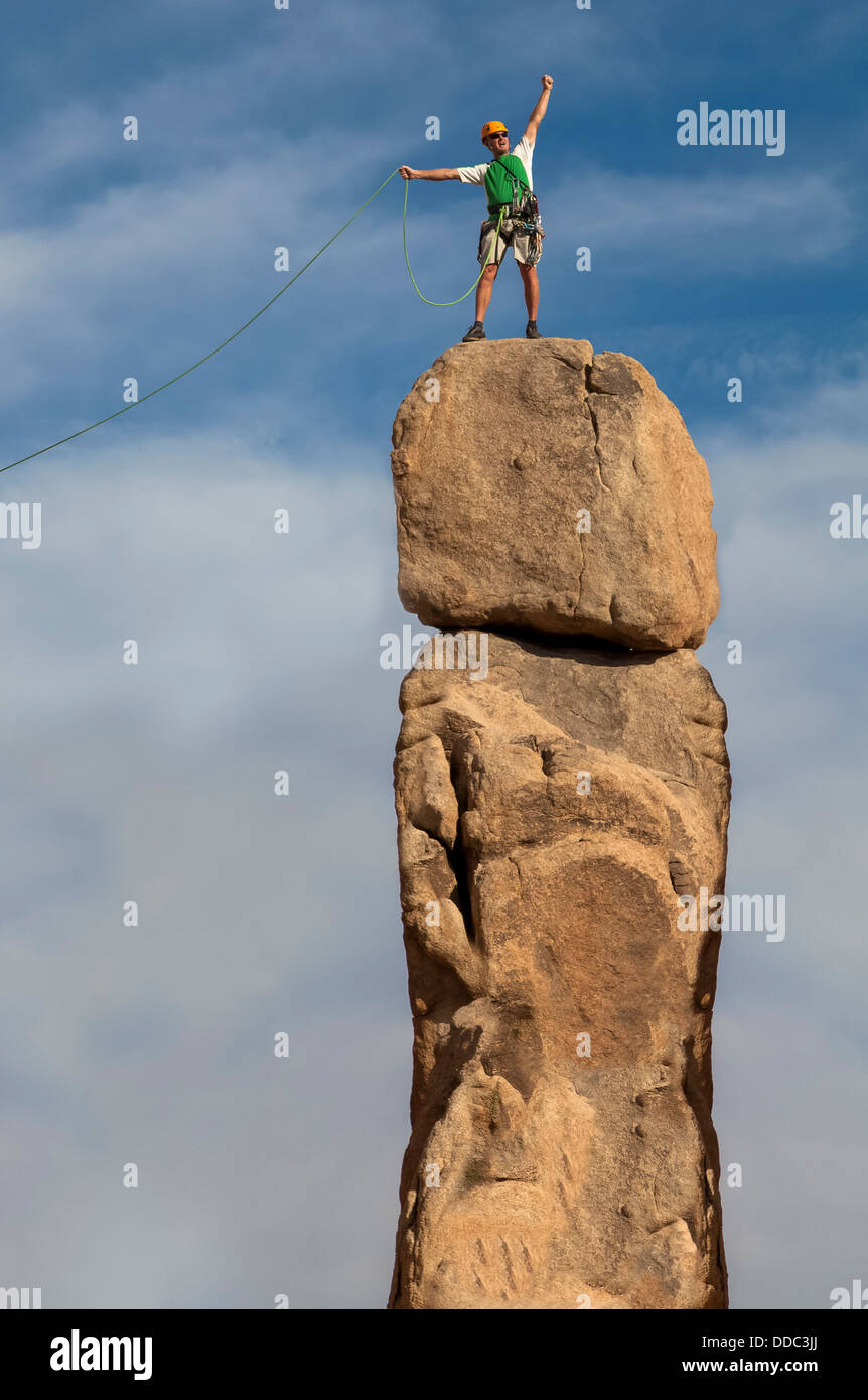 Scalatore maschio conquista la vetta di un impegnativo guglia di roccia. Foto Stock