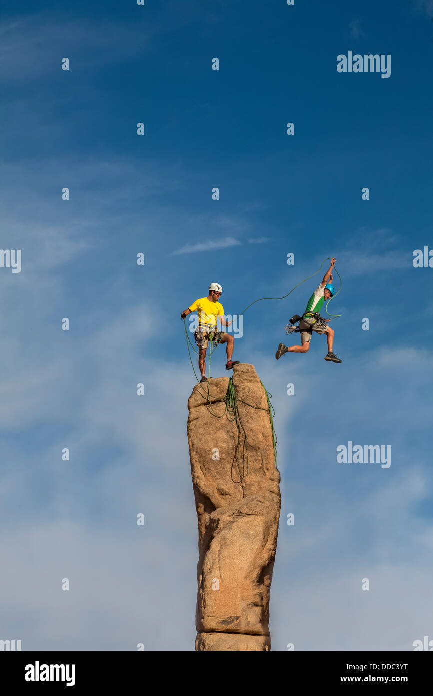 Team di arrampicatori maschio conquistare la vetta di un impegnativo guglia di roccia. Foto Stock