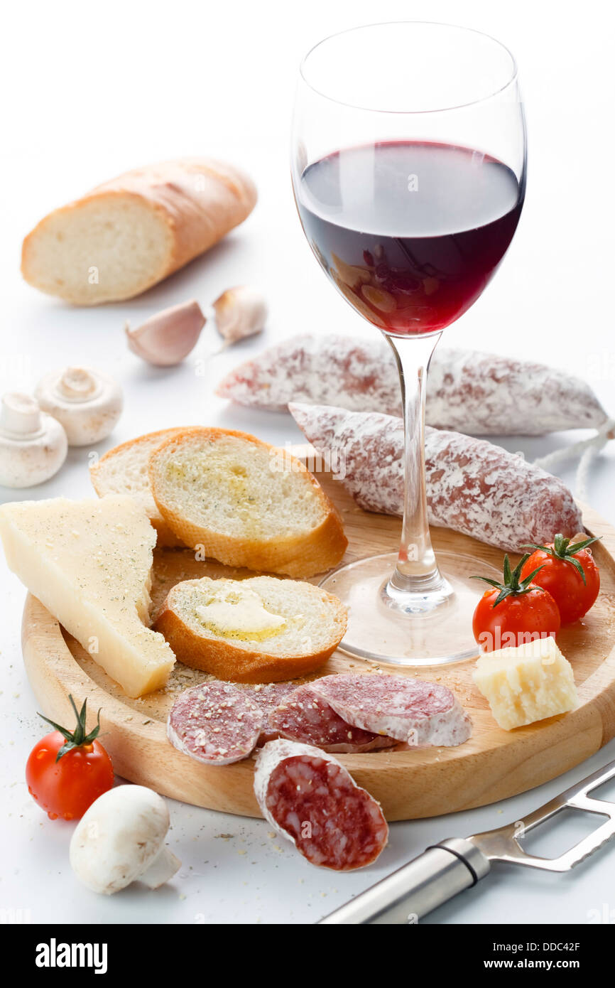 Wineglass con vino rosso e assortimento di formaggi e frutta su sfondo bianco Foto Stock