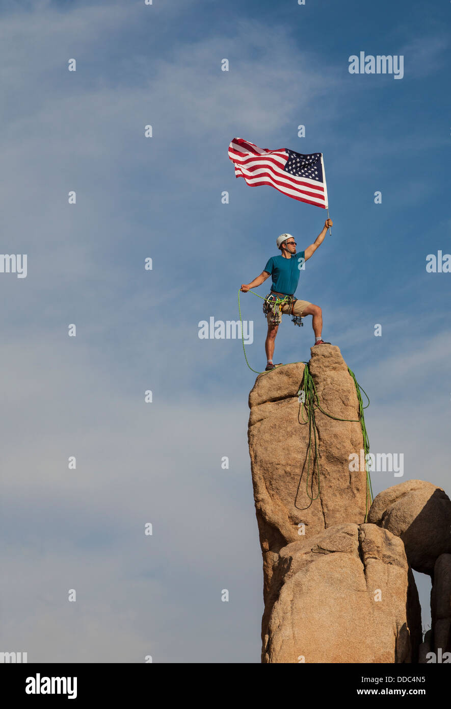 Scalatore maschio conquista la vetta di un impegnativo guglia di roccia. Foto Stock