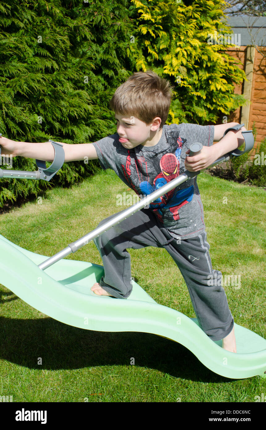 Bambino di otto anni con le stampelle di pensare di essere avventurosi su  un giardino diapositiva Foto stock - Alamy