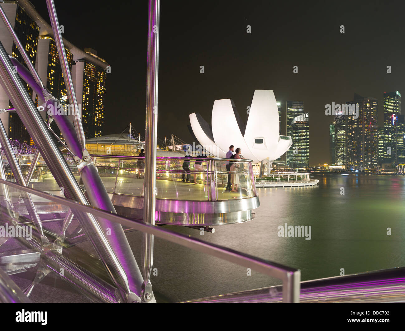 Dh l arte del Museo della SCIENZA MARINA BAY SINGAPORE giovane viewpoint serata luci notturne di Helix bridge turisti cityscape turismo Foto Stock