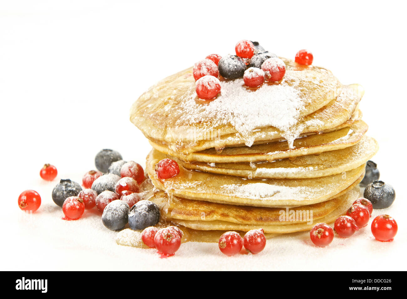 Piccoli pancake e rabboccato con ribes rosso e mirtilli neri su sfondo bianco Foto Stock