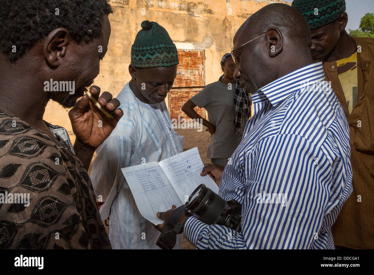 Manager di un no-profit ONG guardando inventario di magazzino Steward in Bijam, un Wolof Village, vicino a Kaolack, Senegal Foto Stock