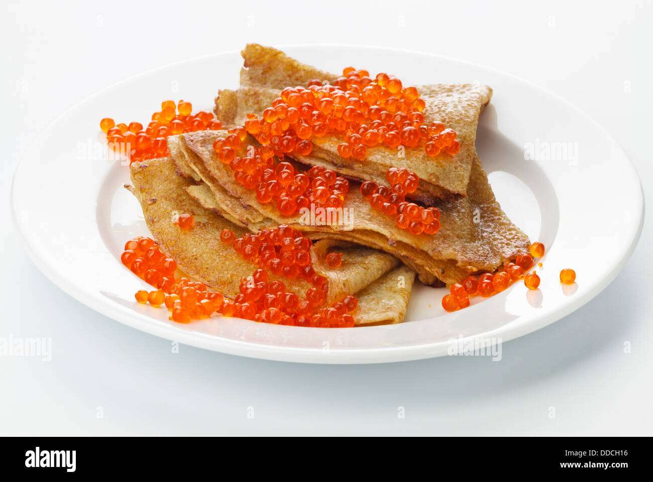 Pancake con caviale rosso su sfondo bianco Foto Stock