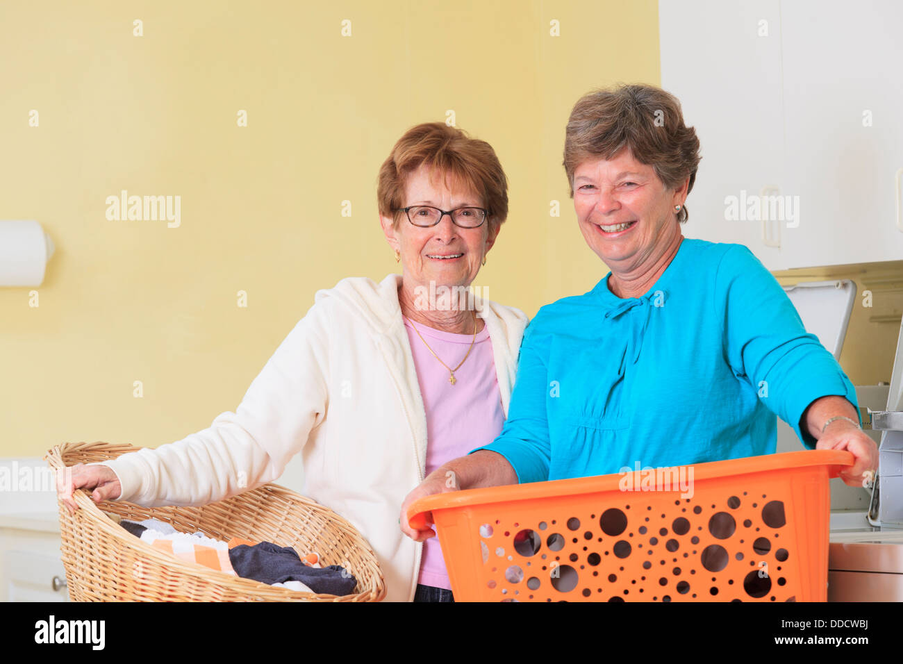 Le donne anziane in una sala lavanderia con cesti Foto Stock
