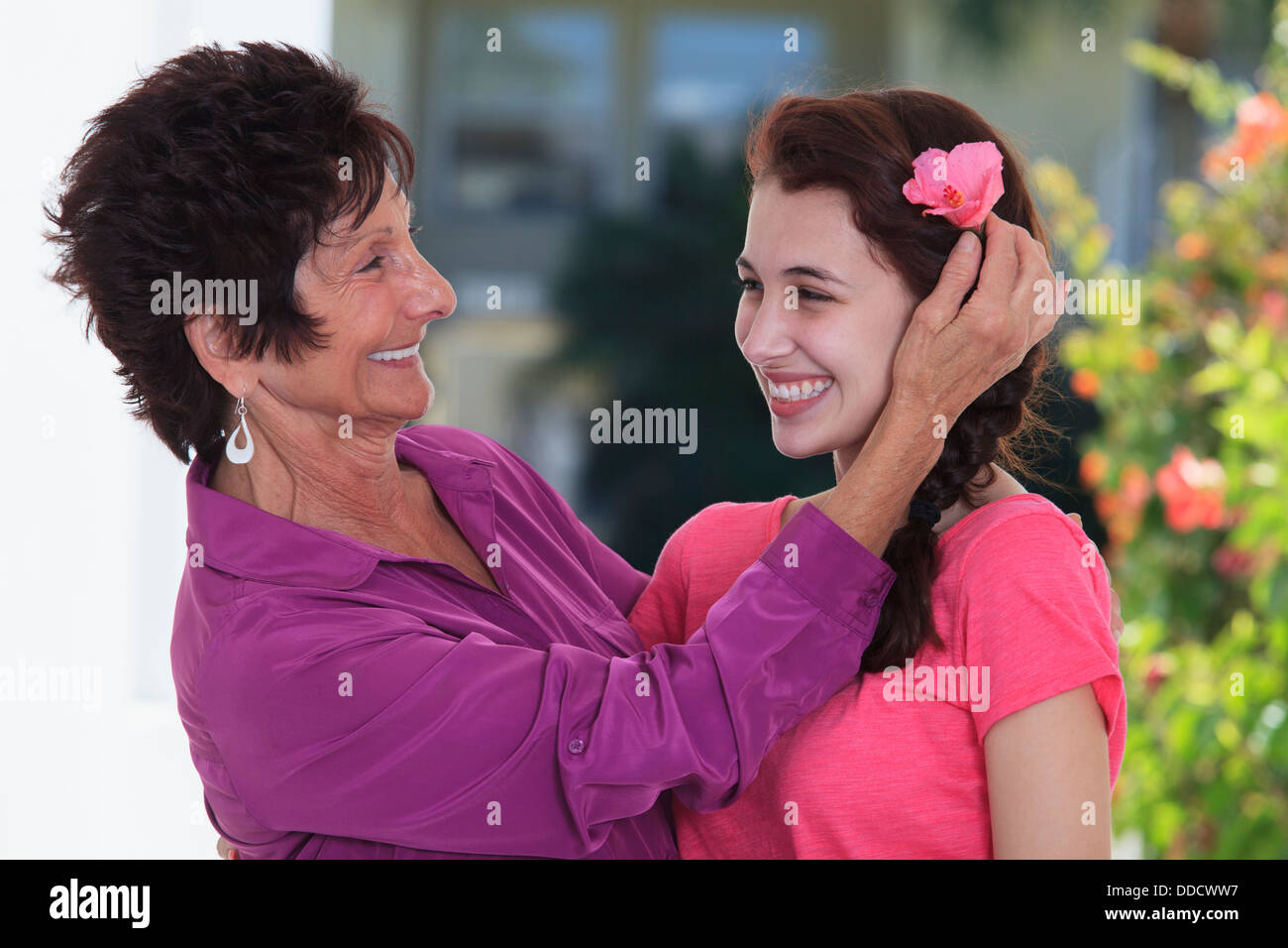 Senior donna sorridente regolare fiore in nipote i capelli Foto Stock