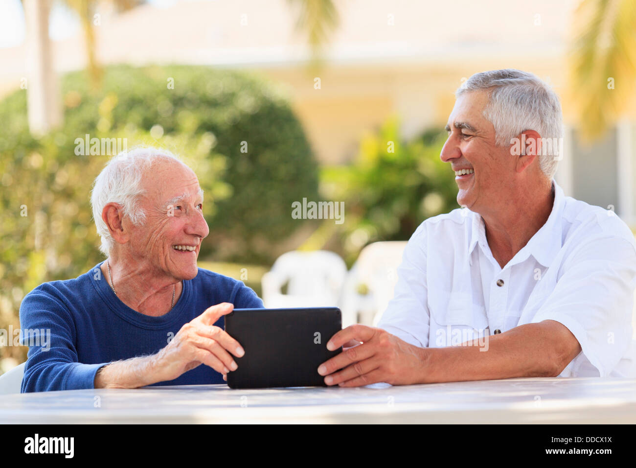 Senior uomo sorridente che mostra una tavoletta digitale a suo padre Foto Stock