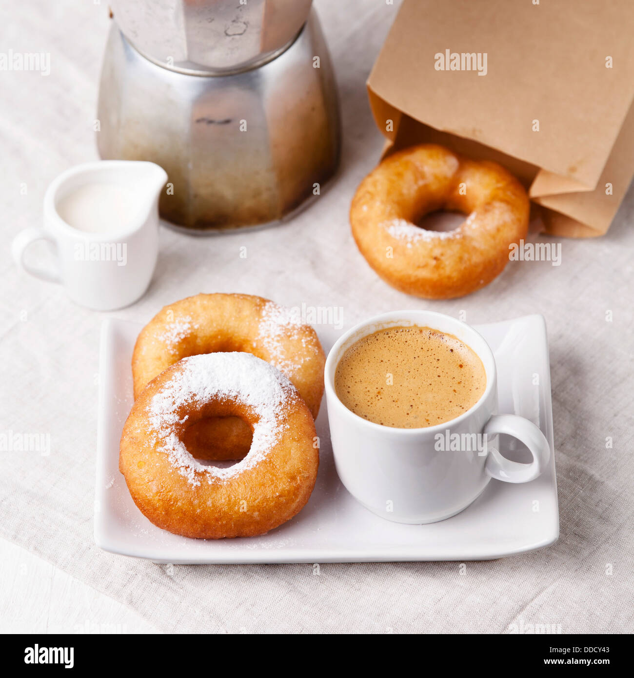 Ciambelle e caffè la mattina sul tavolo per la colazione Foto Stock