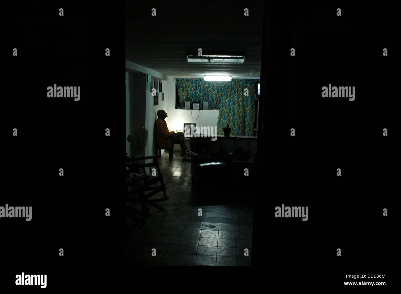 Un anziano orologi cubano televisione in un ambiente poco illuminato home. Foto Stock