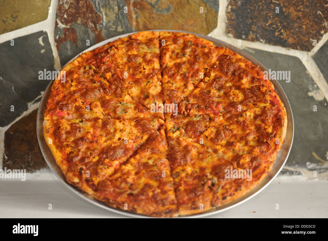 Una pizza si appoggia contro un muro di pietra. Foto Stock