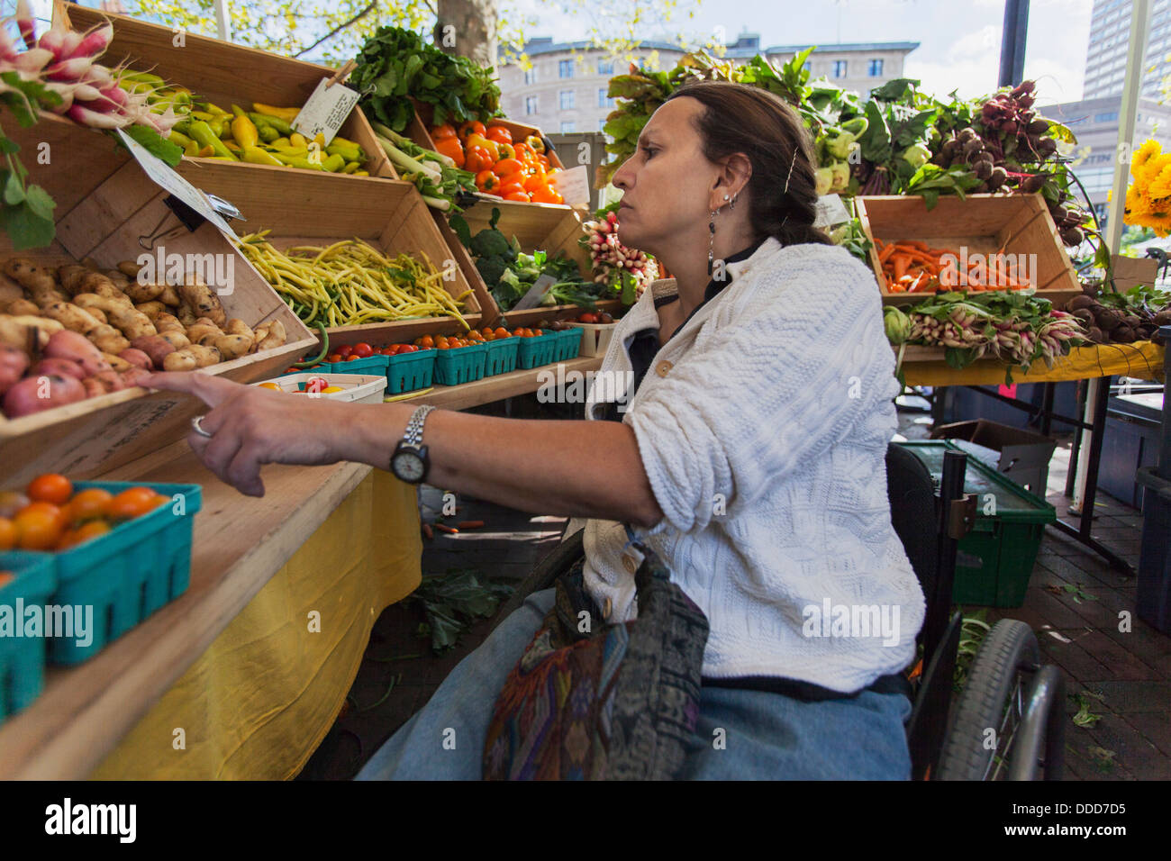 Donna con lesioni al midollo spinale in carrozzella shopping al mercato all'aperto Foto Stock