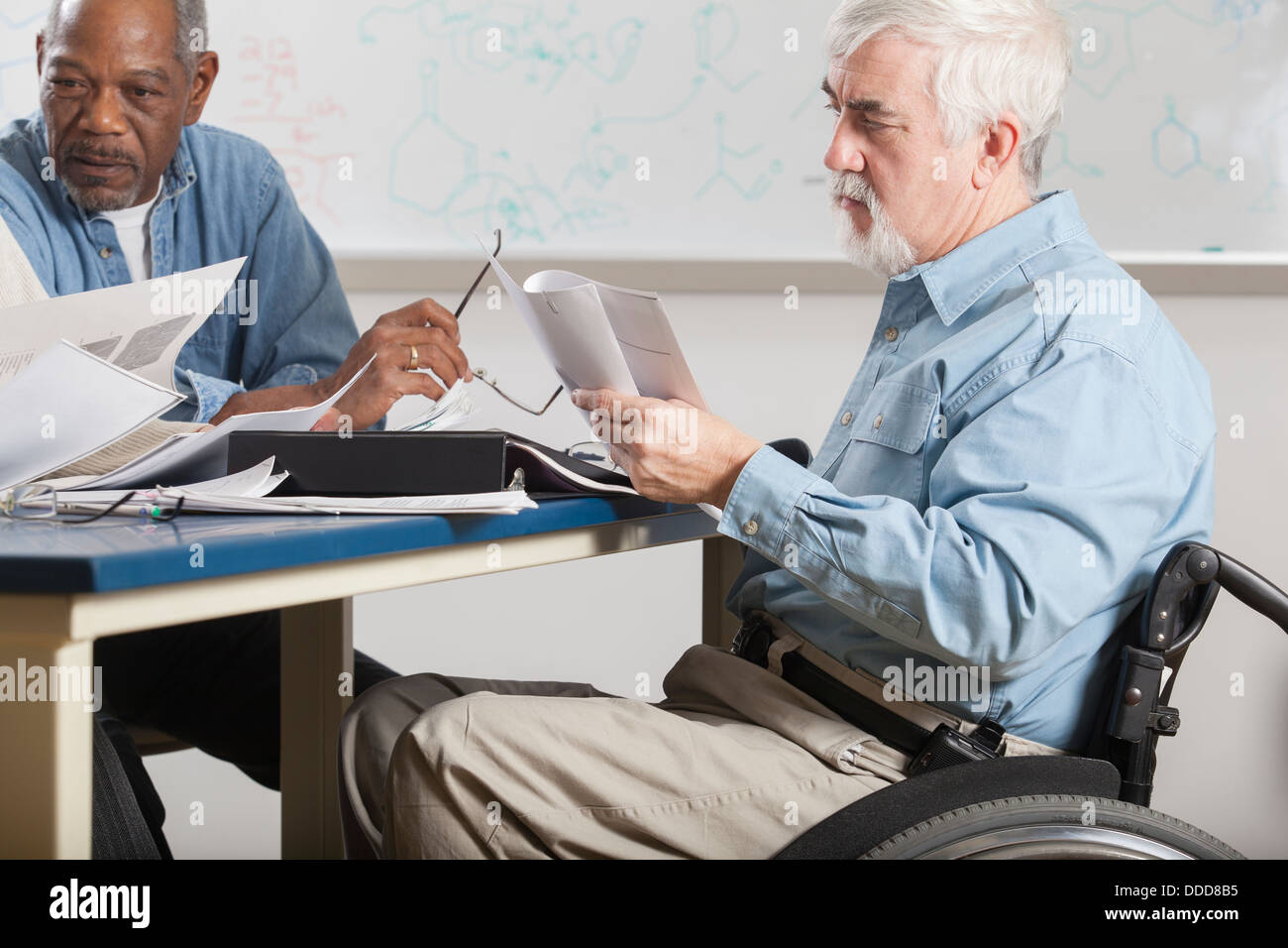 Il Professor con la distrofia muscolare in una sedia a rotelle a un collegio docenti riunione Foto Stock